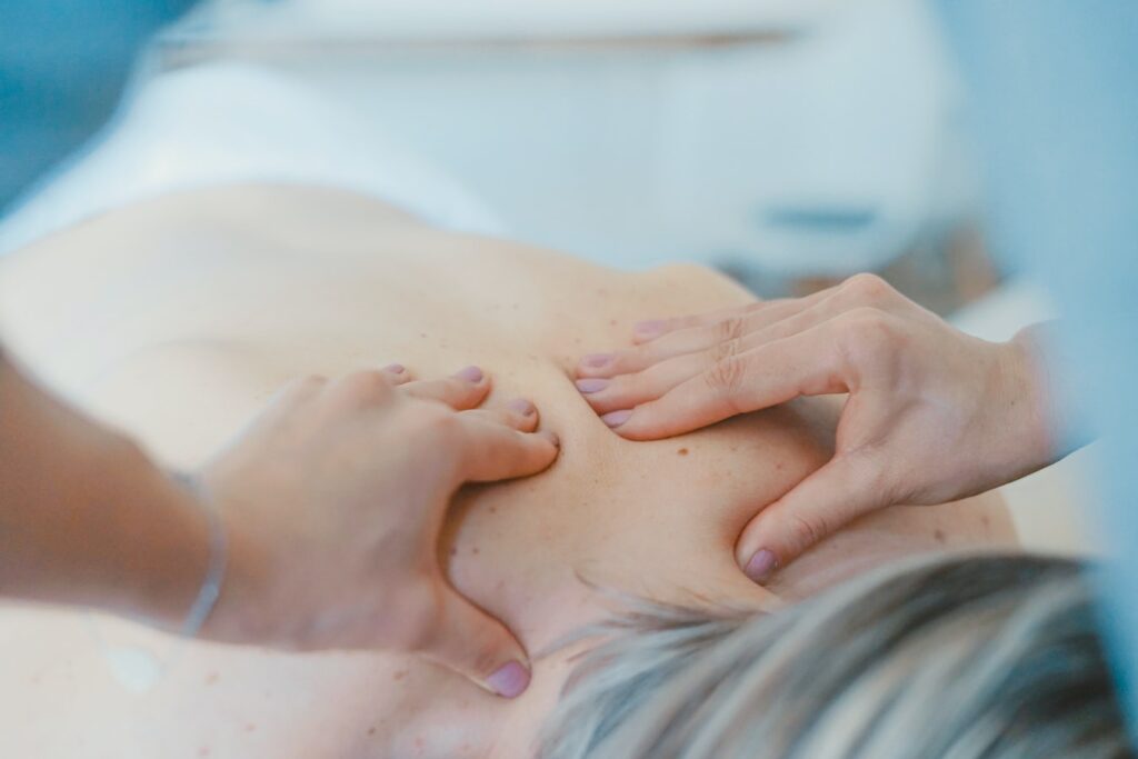 Close-up of hands gently massaging a person’s back in a calm, relaxing setting